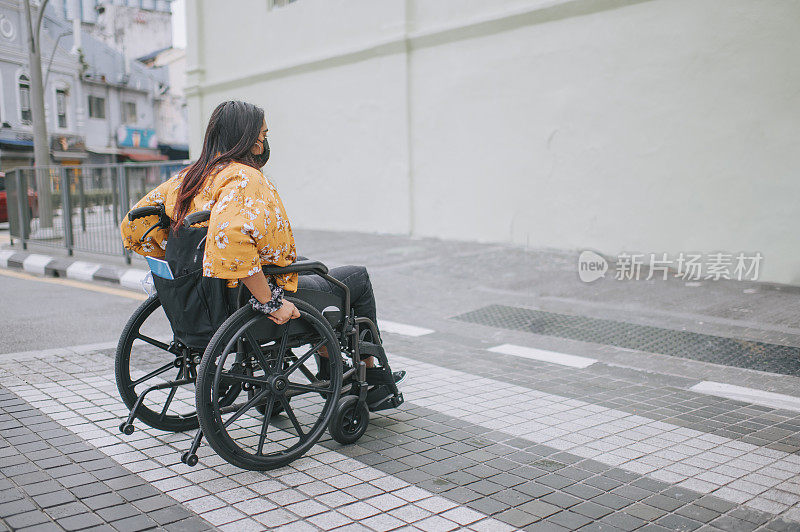 侧视图亚洲印度美丽的妇女残疾人使用轮椅斑马线过马路在城市