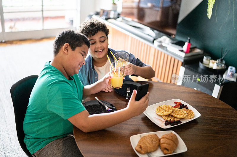 兄弟们在家里吃早餐的时候用智能手机视频通话
