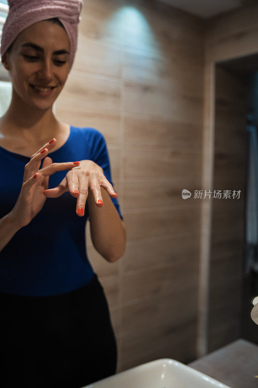 一个女人在浴室里用护手霜擦手