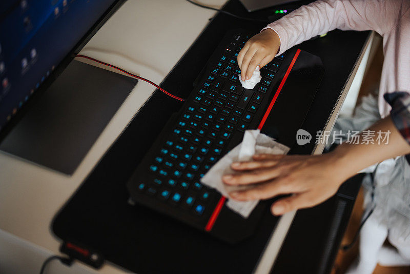母亲和小女儿正在给电脑键盘消毒