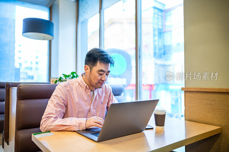 亚洲中年男子在咖啡店使用笔记本电脑