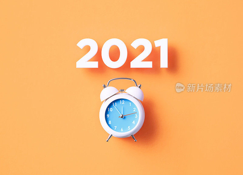 2021年，坐在橙色背景的白色闹钟上