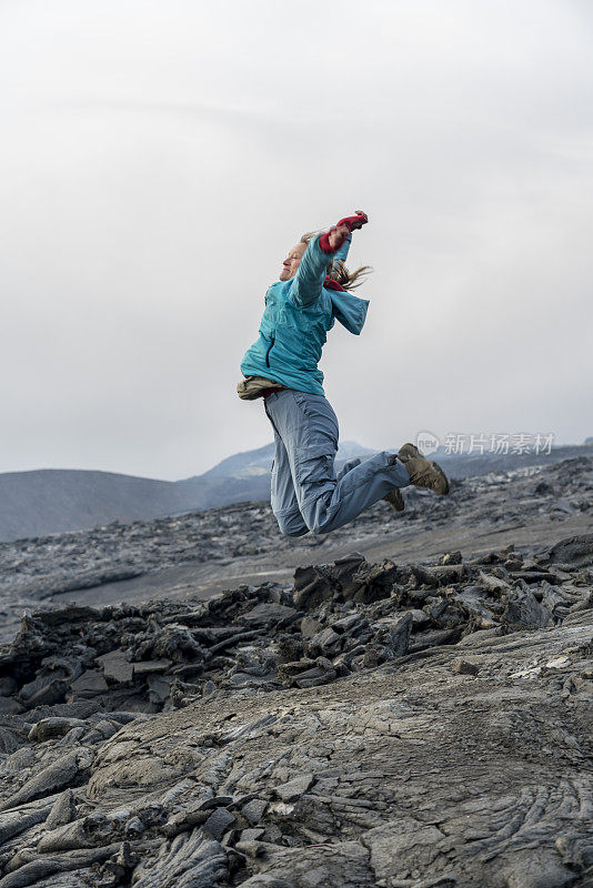 女人们在Fagradalsfjall火山的黑色熔岩上跳跃