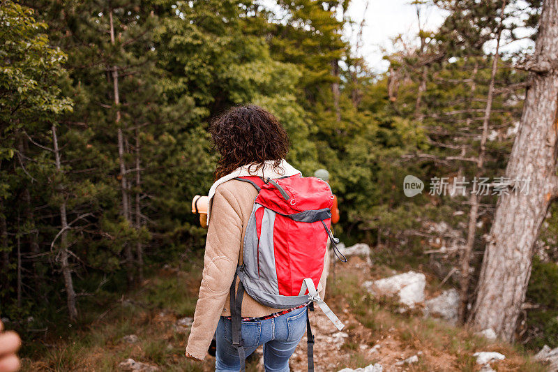 一个在大自然中行走的女性徒步旅行者的后视图。