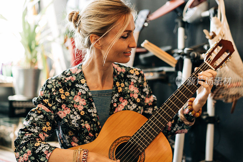 一个微笑着弹吉他的女人的偷拍肖像。