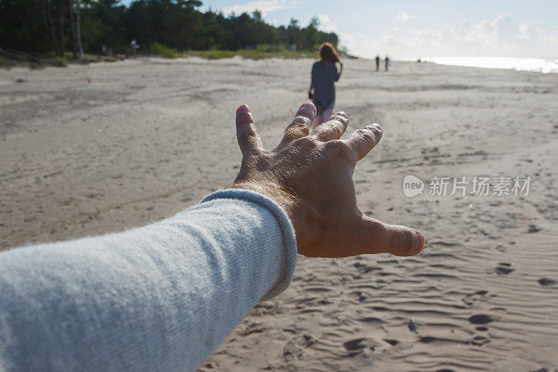 男人在海边伸手去抓女人的视角镜头。