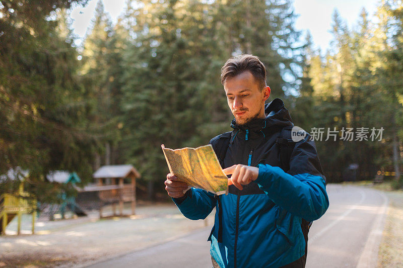一个年轻的男性徒步旅行者在树林里看地图的腰肖像
