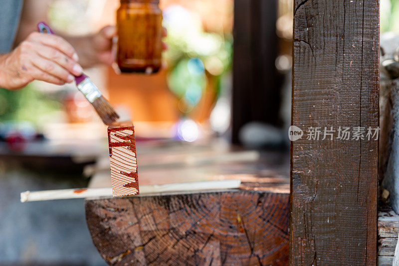 在阳光明媚的日子里，男人正在为家里的露台粉刷木板