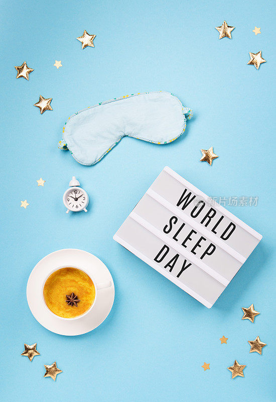 睡眠面具，姜黄金色牛奶拿铁和闹钟在蓝色背景。世界睡眠日概念。