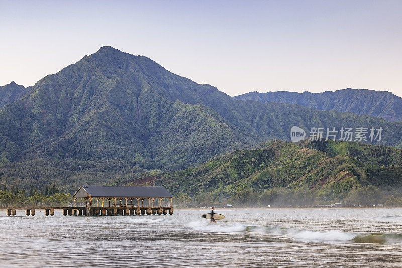 2023年1月8日，美国夏威夷考艾岛，一名冲浪者和著名的哈纳雷湾码头。