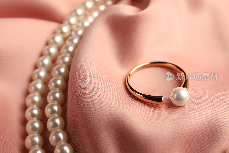 优雅的项链和戒指与珍珠粉红丝绸，特写