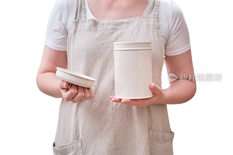厨房里一个女人手里拿着一个敞开的金属罐，孤零零地放在白色背景上。女性的手拿着一个储存容器