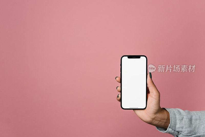 男性手持粉色背景白色屏幕的智能手机