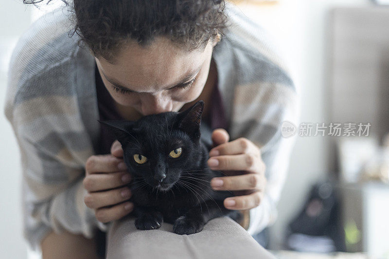 拉丁妇女在家里抚摸黑色宠物猫