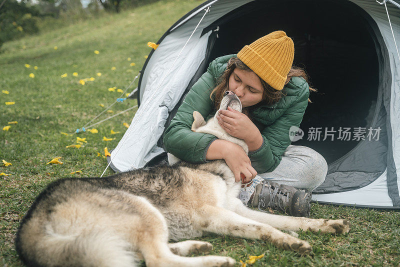 哥伦比亚Peñol，一名年轻女子在帐篷旁与她的宠物玩耍