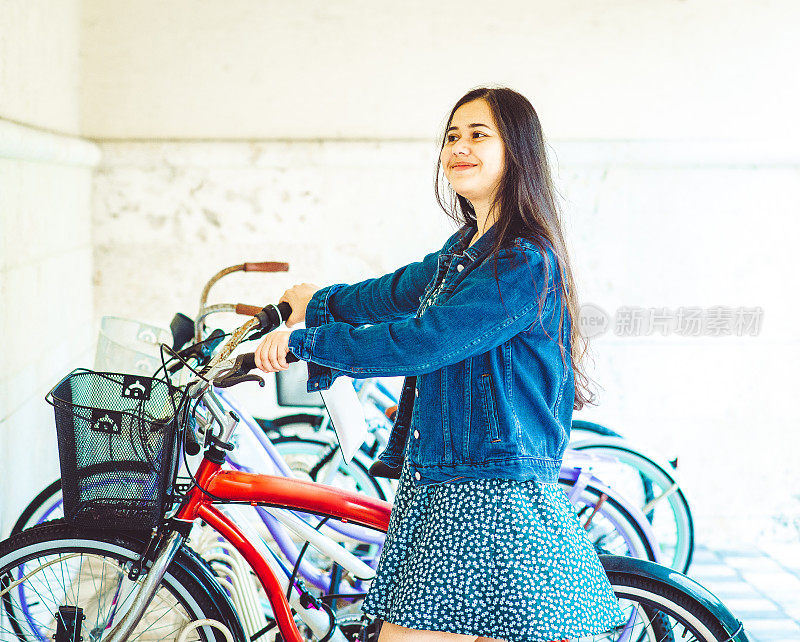 年轻的亚洲女大学生在校园里骑自行车