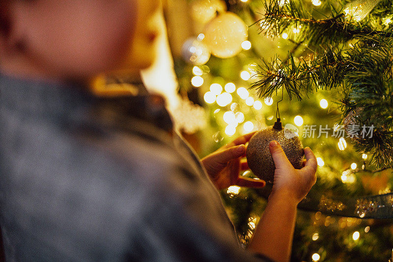 一个小孩拿着家里的圣诞树装饰物的特写