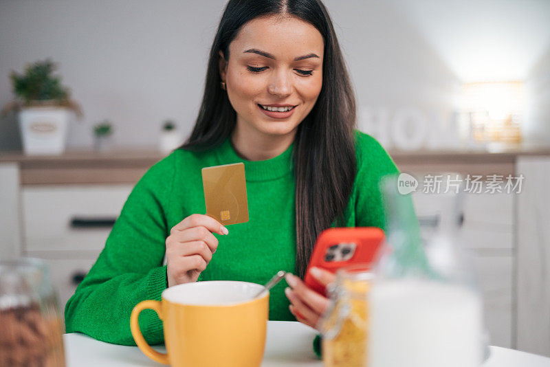 年轻女子一边在厨房吃早餐，一边在网上购物