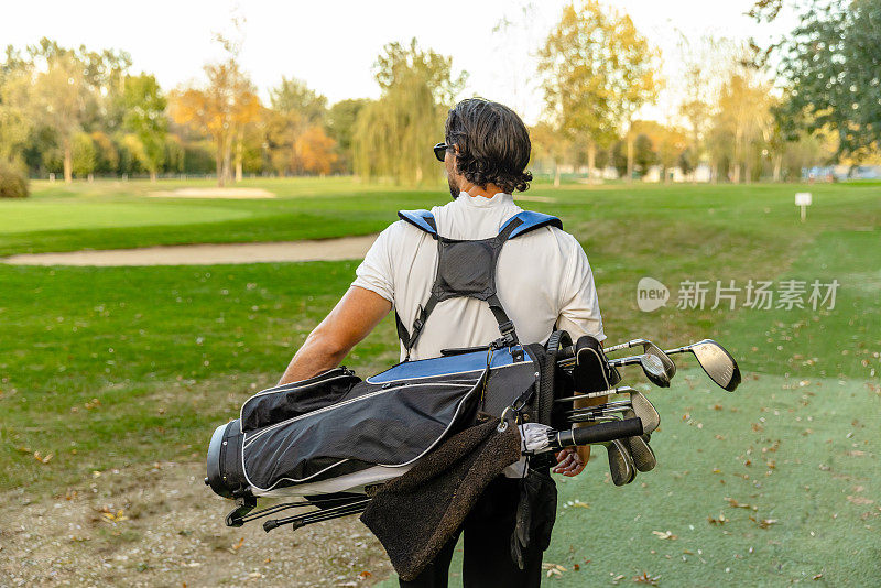 高尔夫球手进入高尔夫球场与包在他的背上-股票照片