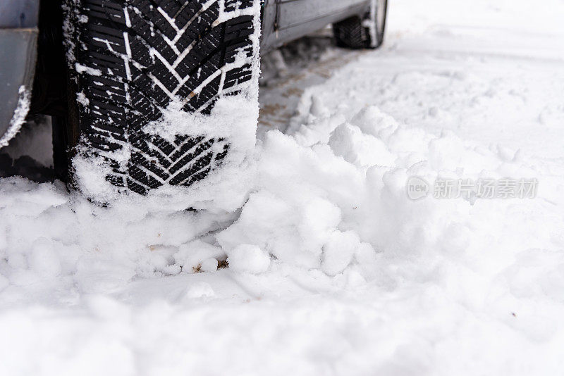 汽车轮胎上的冬季道路覆盖着积雪。车辆行驶在积雪的小巷里。冬季轮胎。汽车轮胎在冬天被雪覆盖的道路上的细节。
