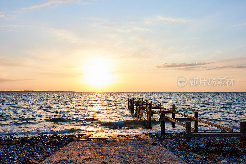 夕阳下明亮的天空映衬着海上废弃的码头