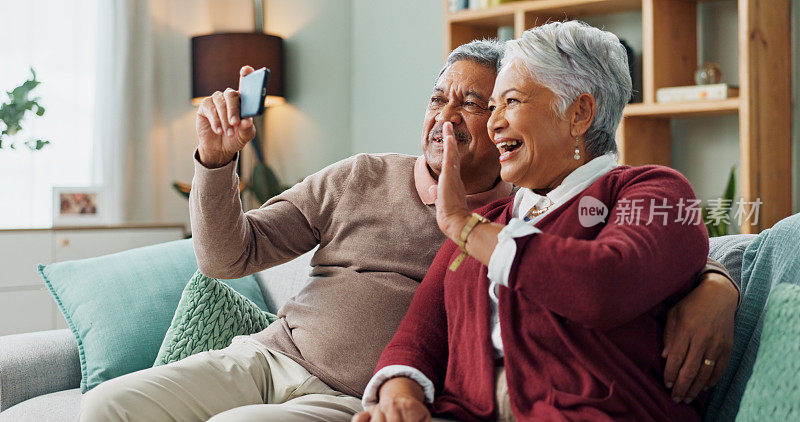 老夫妇，笑声和智能手机在客厅视频通话，联系和沟通。人们，成熟的男人和女人在沙发上，沙发上和房子一起用手机上网聊天