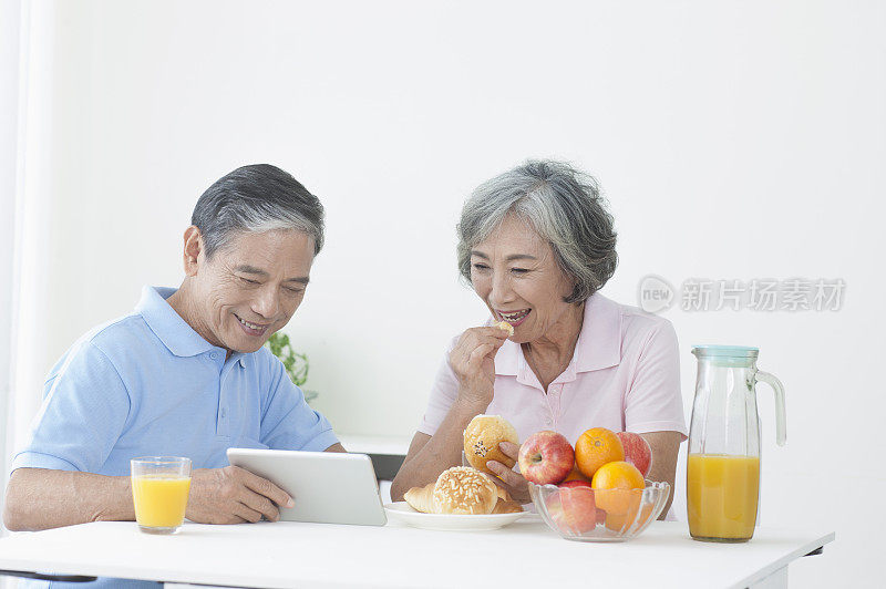 老年夫妻在客厅吃早餐使用平板计算机