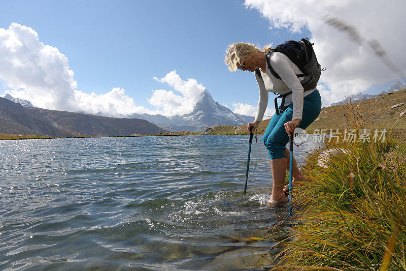 女徒步旅行者在湖水中踩水