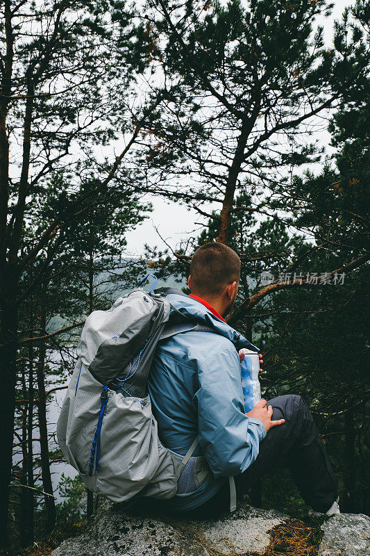 背着背包的男子在挪威的布道石徒步旅行时喝水