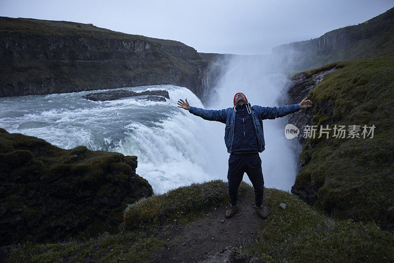 自然美。旅行欣赏瀑布。张开双臂