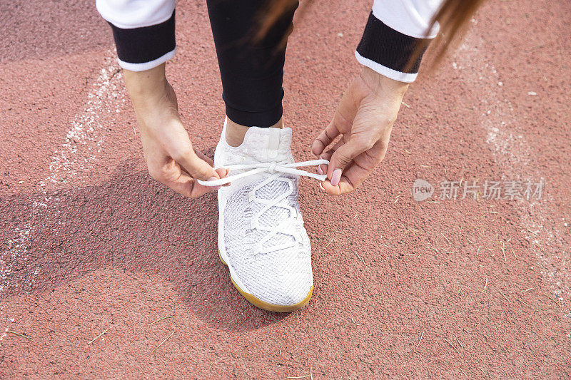 女孩在体育场跑步前系好了他的运动鞋