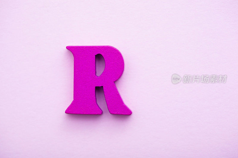 粉红色背景上的木制字母R。