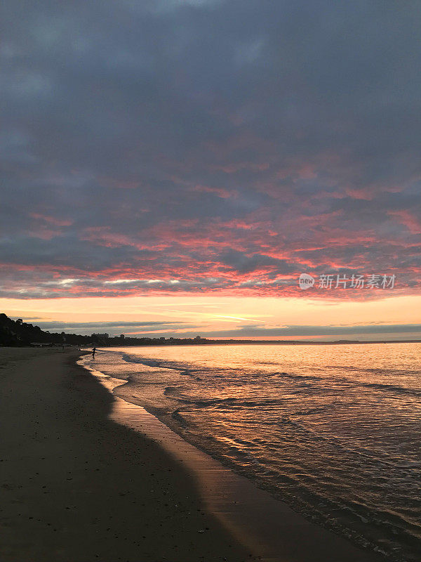 清晨的海滩日出与乌云和粉红色的蓝天，伯恩茅斯海滩日出日落照片，多塞特海岸线，英格兰西南部，英国