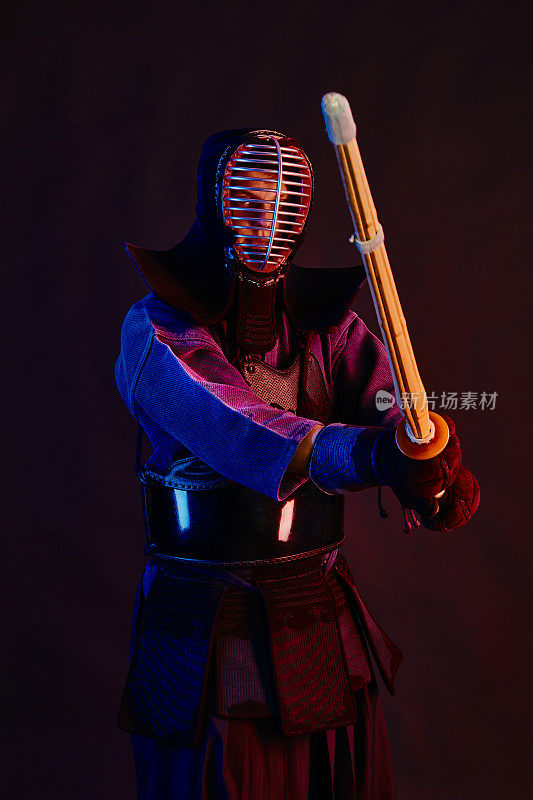 近景，剑道战士穿着盔甲，传统和服，头盔练习武术与shinai竹剑，黑色背景