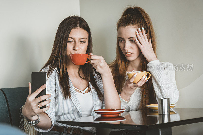 年轻的女性朋友们坐在咖啡馆里，拍下美丽的瞬间