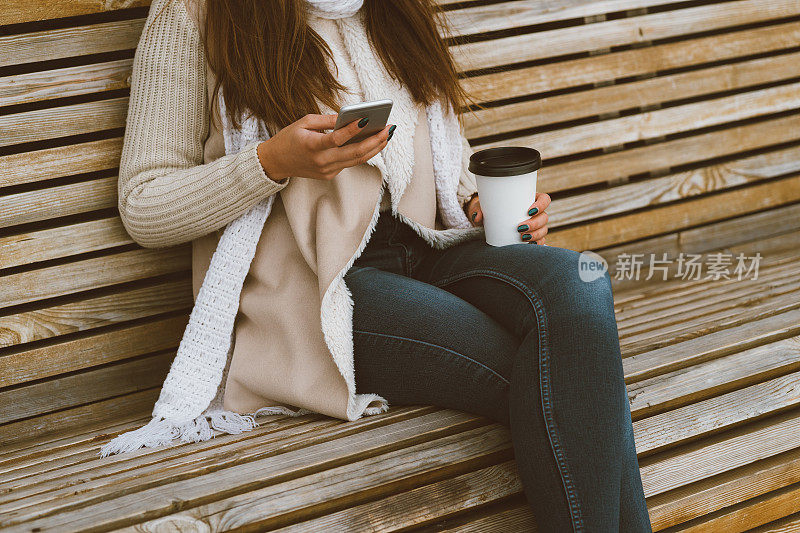 在秋天，在冬天，用塑料杯喝着咖啡，喝着茶，还在打电话。秋冬长发女子坐在长椅上，晒着热饮，拷贝空间
