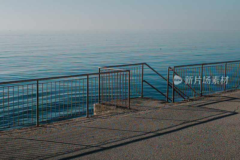 孤独的篱笆由平静的蓝色大海，线条和阴影的图案
