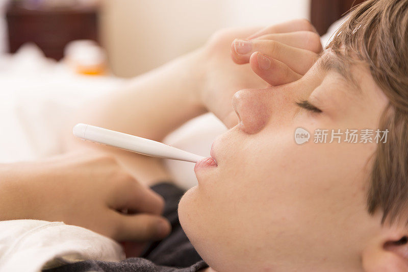 医疗保健:生病的男孩患流感卧床不起。温度计。