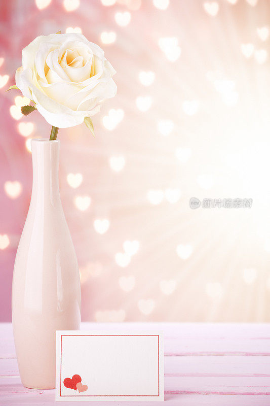 粉红花瓶里的玫瑰和空白卡片