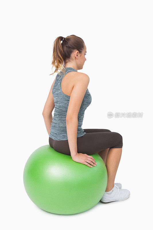 侧面的马尾辫女人坐在健身球上