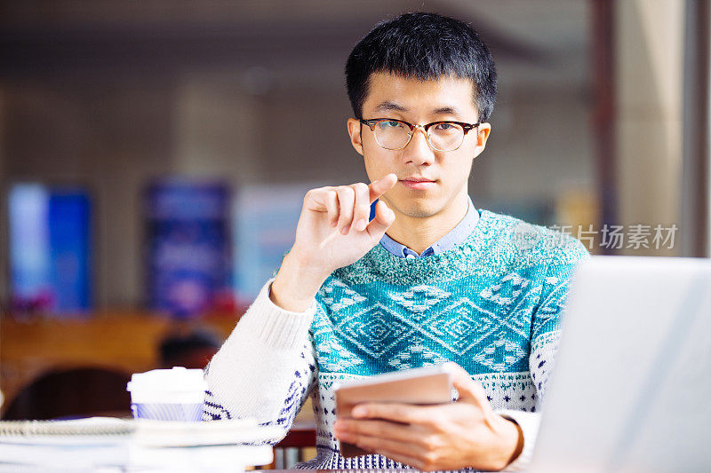 年轻的亚洲男子学生拿着平板电脑