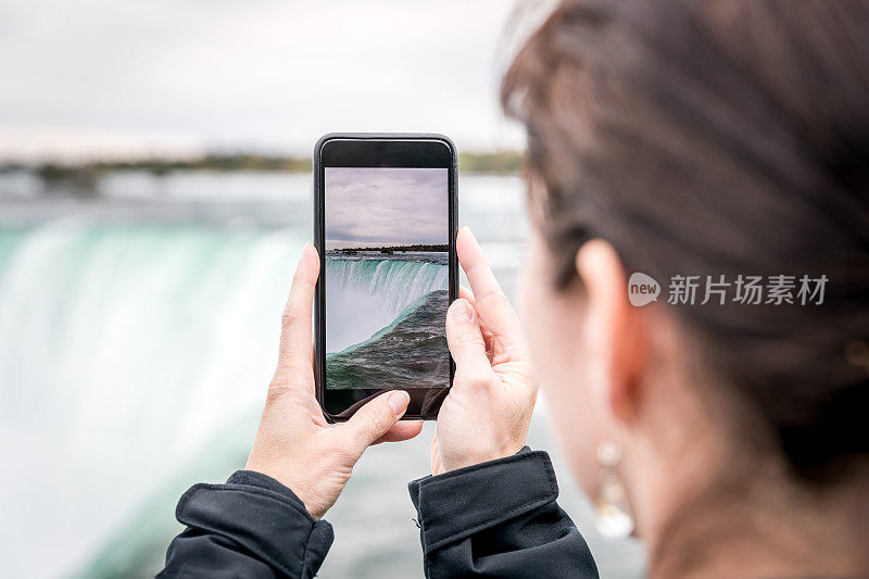 一名女子在尼亚加拉大瀑布用智能手机拍照