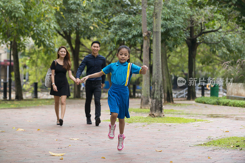 快乐的年轻亚洲家庭漫步在城市公园