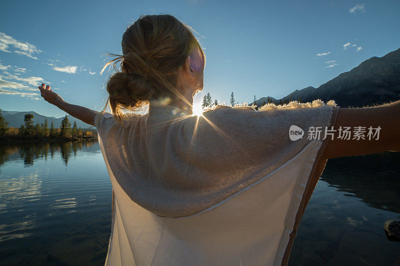 日出时，在湖边欢呼的妇女张开双臂