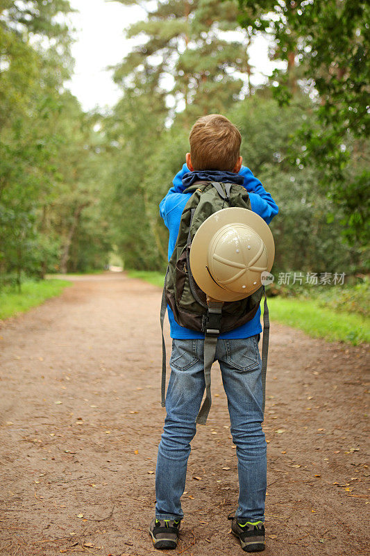 背包徒步男孩在森林里用望远镜看