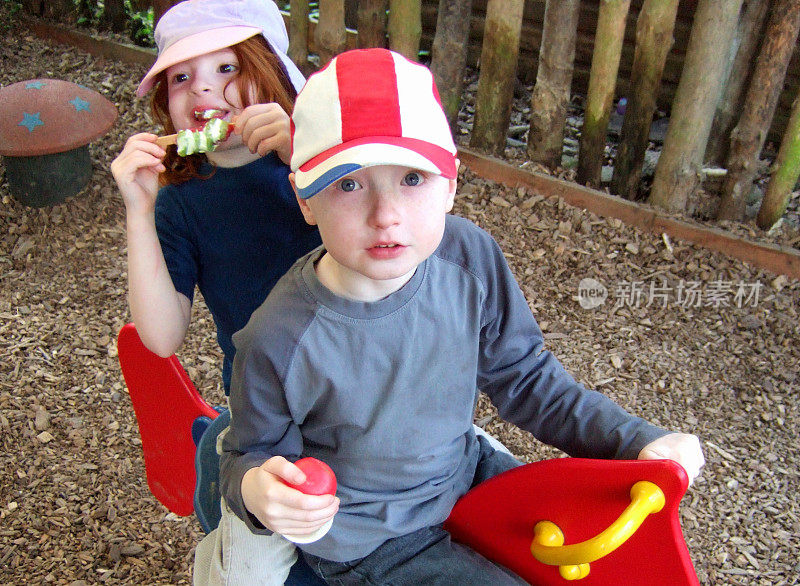 男孩和女孩在儿童操场上玩，吃着冰淇淋