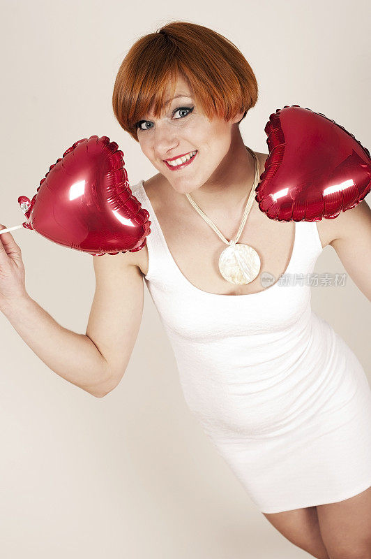 红发年轻女子拿着心形气球