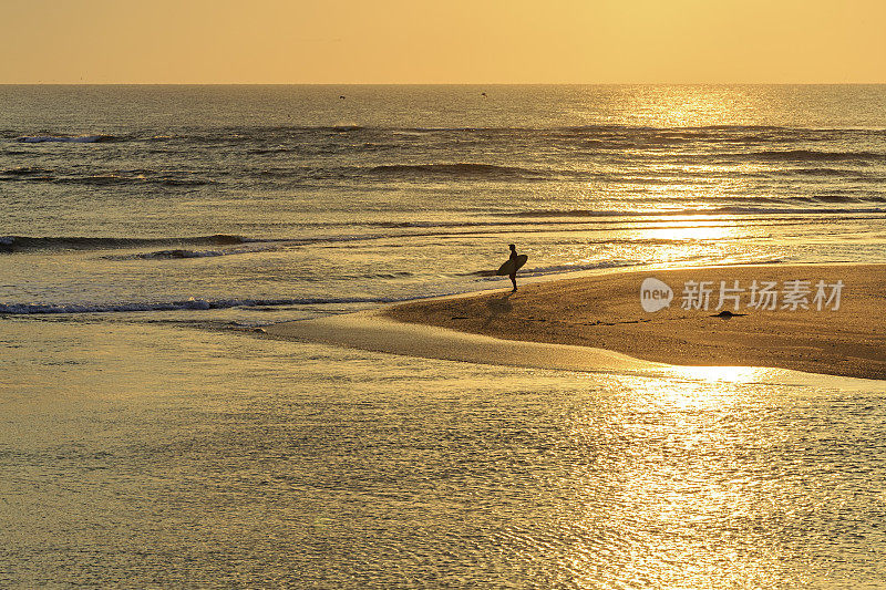 日出时与冲浪者在一个岛屿的海岸