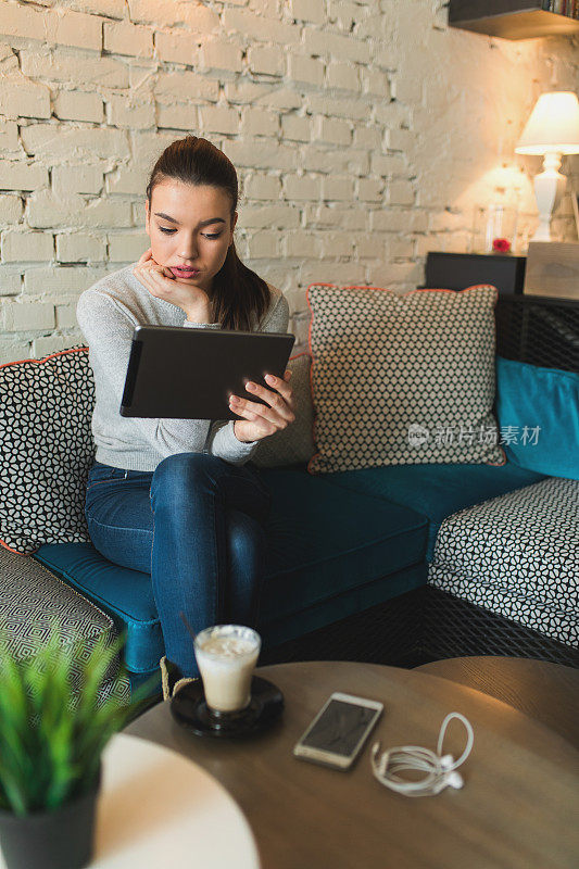 在家里一边喝咖啡一边用平板电脑的女人