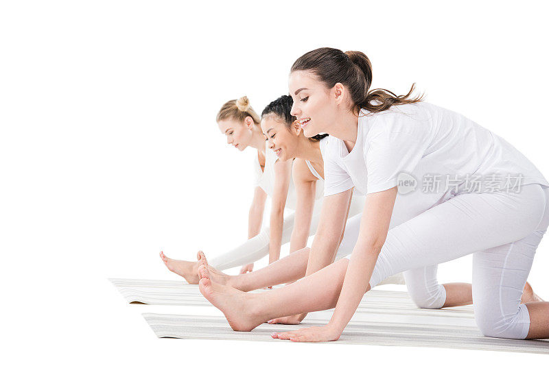 侧面的年轻女性在运动服装练习瑜伽孤立的白色